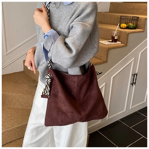 Detail view of large burgundy suede tote bag featuring a stylish zebra print strap