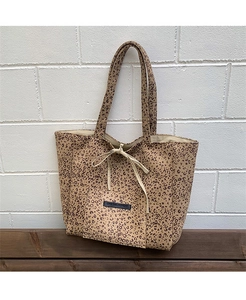 Detail of leopard print suede tote bag with drawstring bow and black brand label
