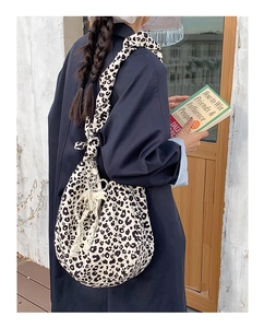 Detail of leopard print tote bag with ruched strap and pearl lace charm on soft fabric
