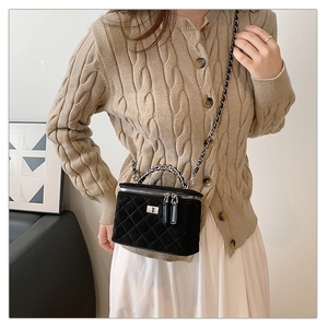 Detail of black quilted velvet vanity case bag with metallic chain and elegant gold clasp