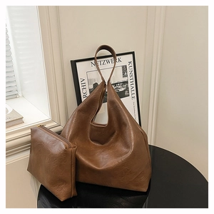 Detail view of premium dark brown leather tote bag and matching pouch on a black table
