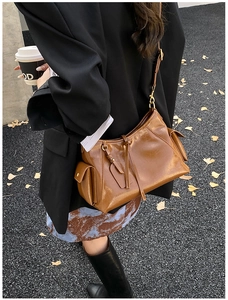 Detail of vintage brown leather tote bag showing side pockets and fringe on autumn street
