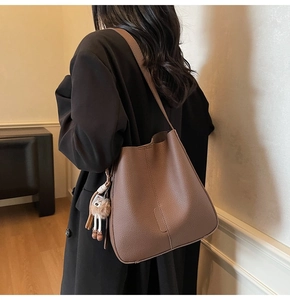 Détail du sac seau marron avec texture de litchi et pendentif en peluche doux