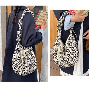 Detail of leopard print hobo bag featuring ruched handle and lace bow decoration