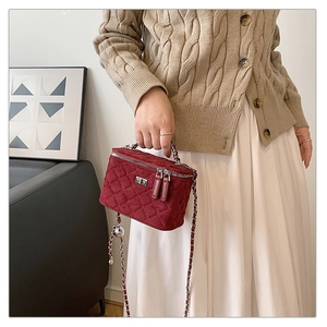 Close-up of burgundy quilted velvet mini box bag with silver metal chain and lock