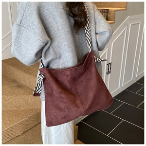Detail of burgundy frosted tote bag with black and white striped wide shoulder strap