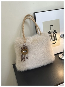Close-up of cream plush tote bag with woven handles and cute cat charm decoration