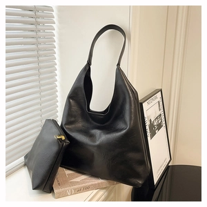 Macro view of black leather tote bag texture and small matching pouch with gold zipper
