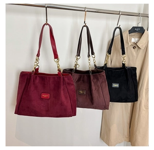 Detailed view of three large suede tote bags in burgundy, coffee, and black with chain straps