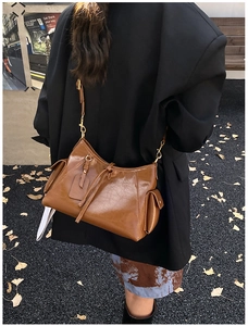 Detail of a dark brown vintage leather tote bag shown on a model in urban setting