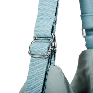 Detail view of adjustable wide fabric shoulder strap with silver metal buckle on tote bag