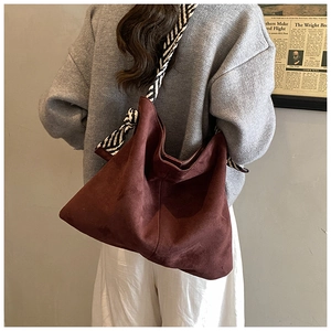 Detail of burgundy suede tote bag featuring elegant black and white striped silk scarf