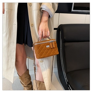 Detail of a brown quilted crossbody box bag with silver twist lock and chain strap
