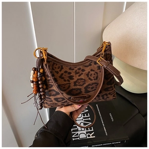 Gros plan du sac à bandoulière léopard avec lanière en cuir et pompon en perles de bois