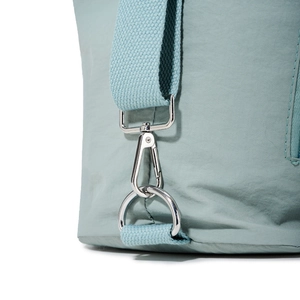 Detail of light blue nylon tote showing silver metal strap hooks and durable fabric texture