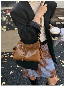 Close-up of brown vintage leather tote bag with utility pockets and drawstring detail