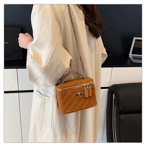 Brown quilted suede crossbody bag with metal twist lock and chain strap on a model
