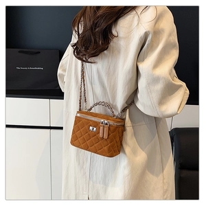 Detailed side view of caramel quilted vanity bag with chain strap on a stylish model