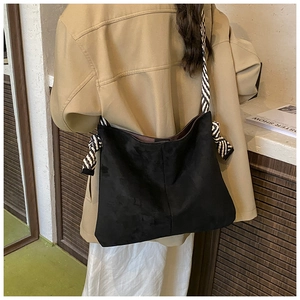 Detail of black suede tote bag with stylish black and white striped crossbody strap