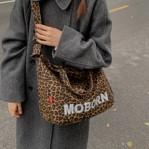 Détail du grand sac cabas en toile léopard avec bandoulière réglable porté par un mannequin