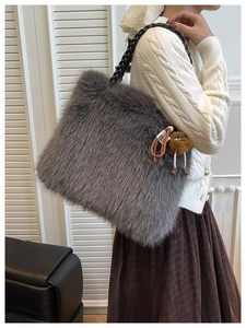 Detail of grey faux fur tote bag with braided handles and a cute monster pendant accessory