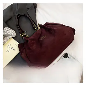 Macro detail of burgundy suede tote bag featuring premium leather strap and gold chain link