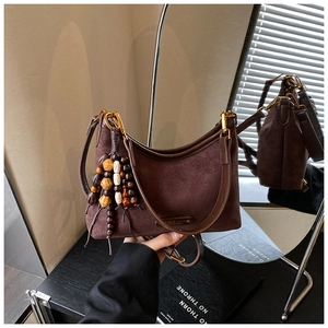 Détail du sac croissant en daim marron foncé avec charme en bois et logo métallique