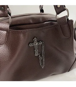 Detail of dark brown lychee leather handbag with vintage metal gothic cross and chain