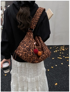 Detail of a large leopard print tote bag with colorful plush charms and drawstring closure