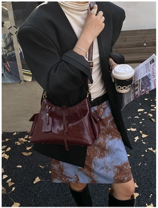 Detail of vintage burgundy tote bag with side pockets and tassels on a street model