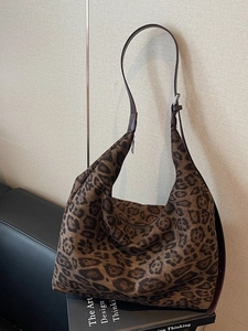 Chic leopard print hobo bag with adjustable brown leather strap on a sofa
