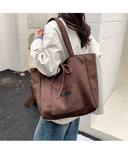 Close-up of leopard print tote bag with exterior pocket and bow detail worn outdoors