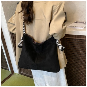 Detail of matte black hobo bag with distinctive black and white striped strap accent