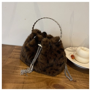Close-up of fluffy dark brown faux fur bucket bag with silver metal ring handle and chain