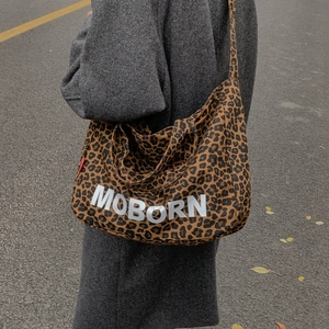 Détail d'un sac cabas en toile léopard avec lettrage Moborn et large bandoulière de mode