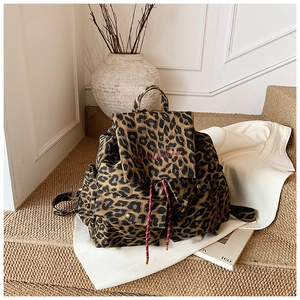 Macro view of leopard print canvas backpack showing red embroidery and rope drawstring details