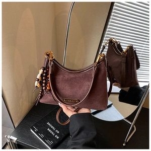 Détail du sac croissant en daim marron foncé avec perles en bois et ferrures dorées