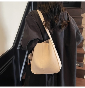 Détail du sac seau en cuir litchi blanc cassé avec un charmant petit ours en peluche