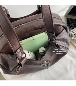 Detailed close-up of dark brown leather tote bag with front pocket showing tablet and bottle