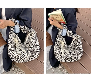 Detail of leopard print tote bag featuring pleated handles and lace bow charm