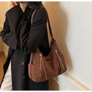 Detail view of large brown frosted leather hobo bag with zipper accents on model
