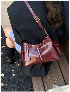 Detail of burgundy hobo bag with oily leather finish and side pockets in autumn setting
