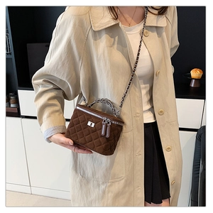 Detail of a brown quilted box bag with silver chain and matte texture on a model