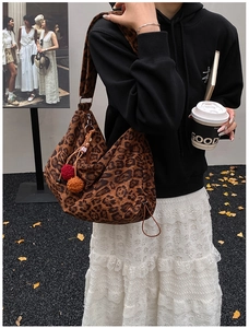 Close-up of leopard print canvas tote bag with colorful pompom charms and wide strap