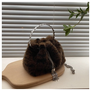 Detailed view of brown plush bucket bag with silver metal ring handle and chain strap