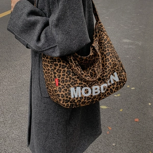 Détail du grand sac cabas en toile léopard avec logo porté sur un manteau gris foncé