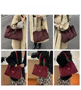 Detail view of burgundy suede tote bag with leather handles and gold chain accents
