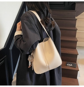 Détail du sac seau beige avec cuir texture lychee et breloque pompon en peluche