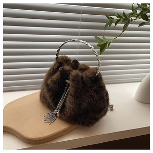 Macro detail of brown faux fur bucket bag featuring silver metal chain and woven handle