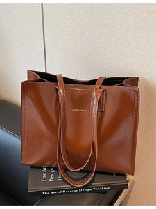 Braune Hochglanz-Tragetasche mit Fashion & Bags Logo auf schwarzen Büchern